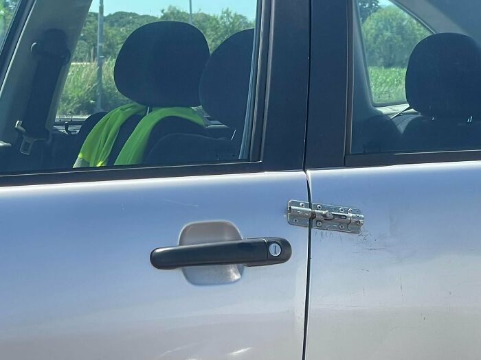 Car door secured with an unusual metal latch, showing a creative example from bad drivers documented in a Facebook group.