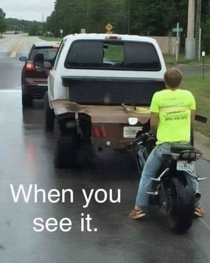Man on motorcycle closely following a pickup truck with a damaged rear tire on a wet road, examples of bad drivers.