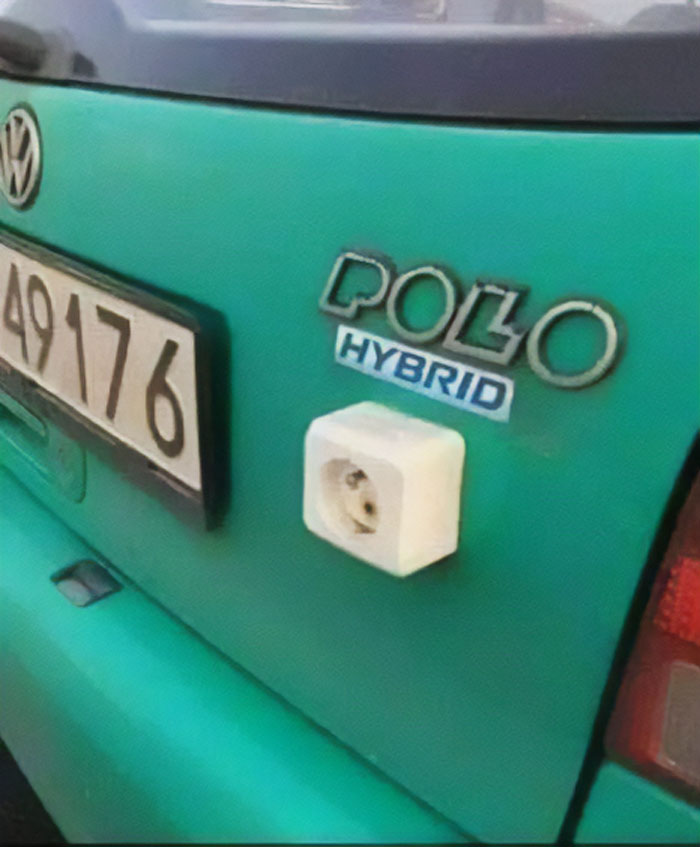 Close-up of a funny car modification showing a green Volkswagen Polo hybrid with an electrical outlet on the back.