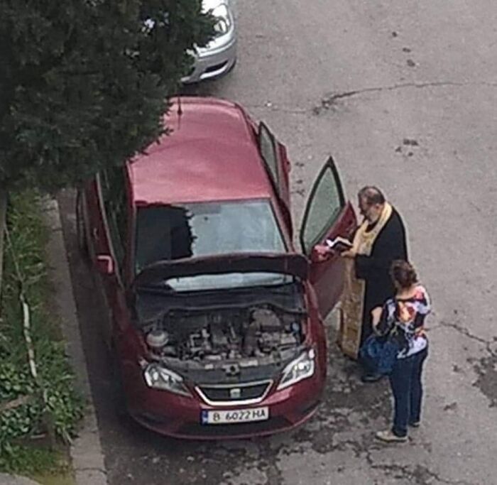 Two people standing next to a red car with its hood and door open, illustrating examples of bad drivers.