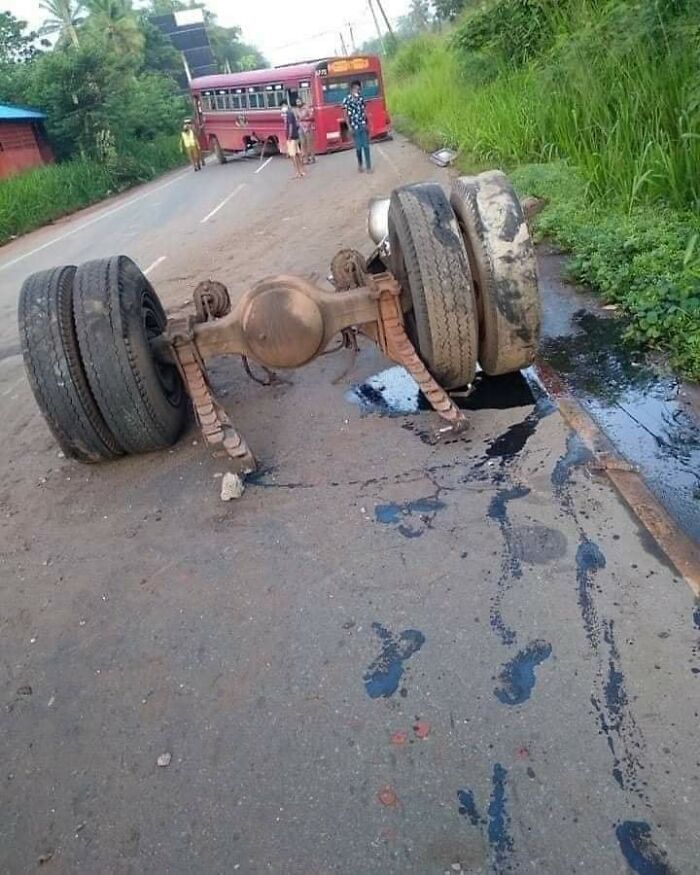 Detached truck axle and tires on road with bus and people in background, example of bad drivers documented in Facebook group.