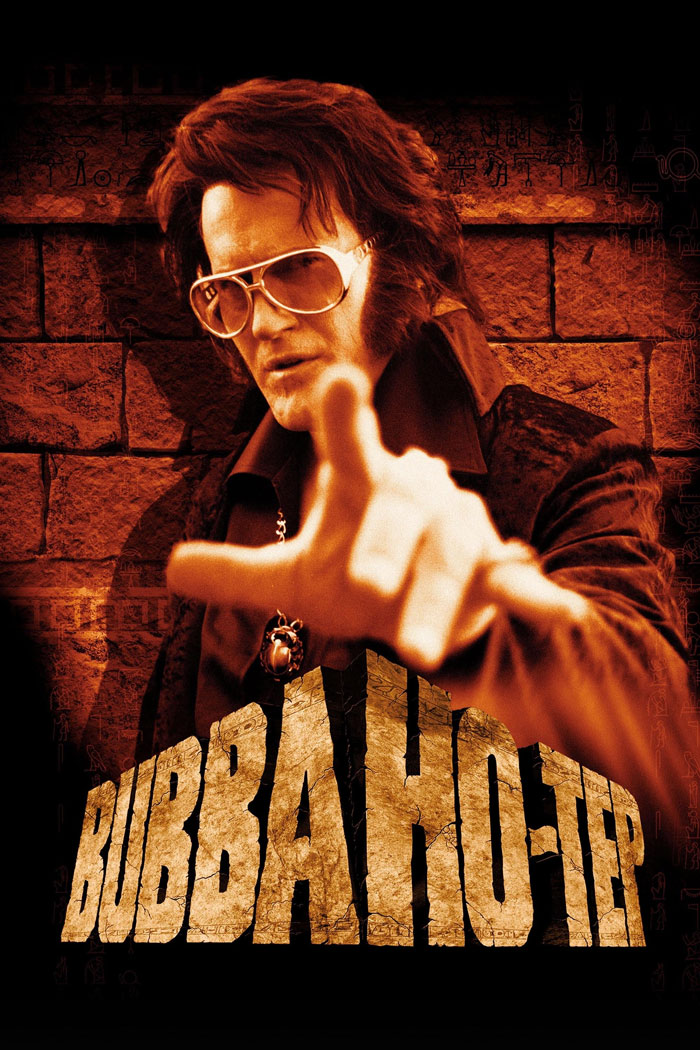 Character dressed as a vintage Elvis with sunglasses pointing forward in a horror comedy movie poster background.