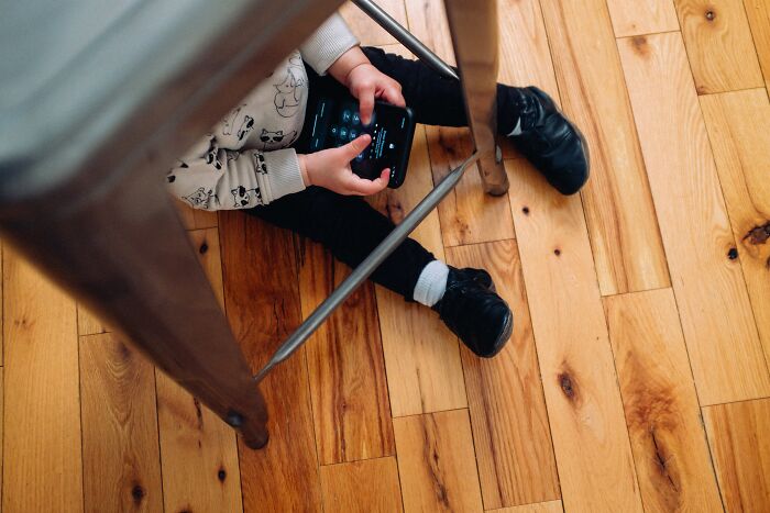 Child sitting on wooden floor holding a handheld gaming device reflecting on what was actually better in the past.