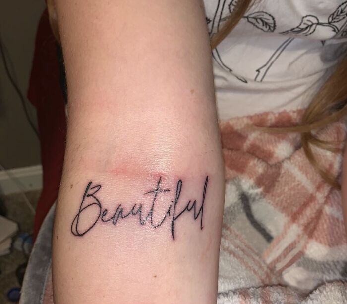 Tattoo of the word "Beautiful" on an arm in elegant script design.