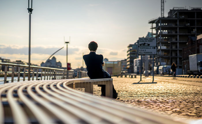 Man sitting alone on a curved bench by the waterfront, reflecting on things guys should never say to partners.