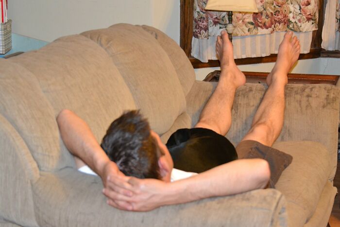 Man relaxing on a beige couch with legs up, illustrating things guys should never say to their partners advice.
