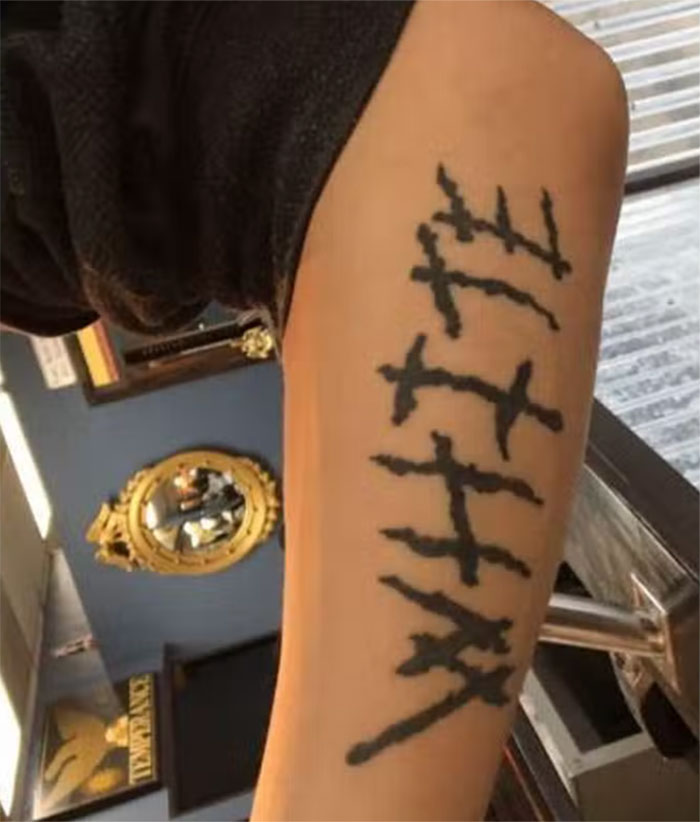 Tattoo of five vertical lines with black ink on a person's upper arm, considered a major red flag by some people.