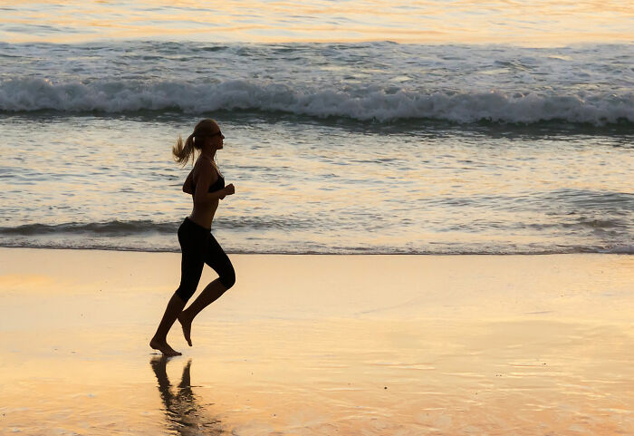 Woman jogging on the beach at sunset reflecting on things guys should never say to their partners for healthy relationships.