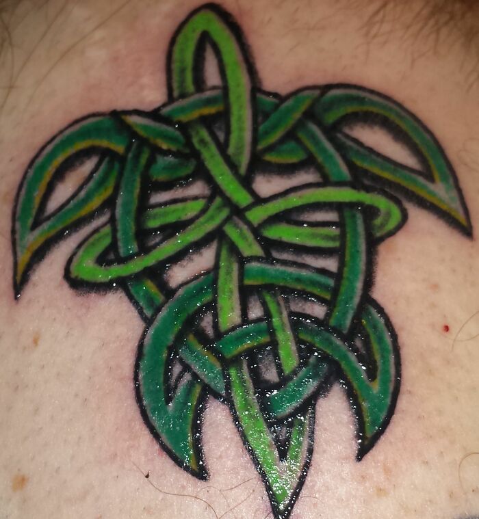 Green Celtic knot tattoo with intricate design on skin.
