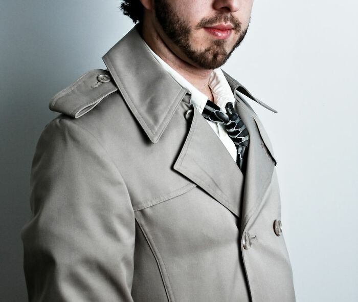 Man in beige trench coat and loosened tie, representing things guys should never say to their partners in relationships.