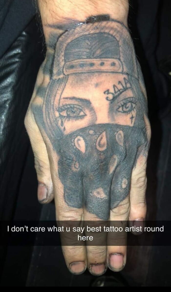 Tattoo of a masked face on a hand, part of a collection of horrible tattoos judged online.