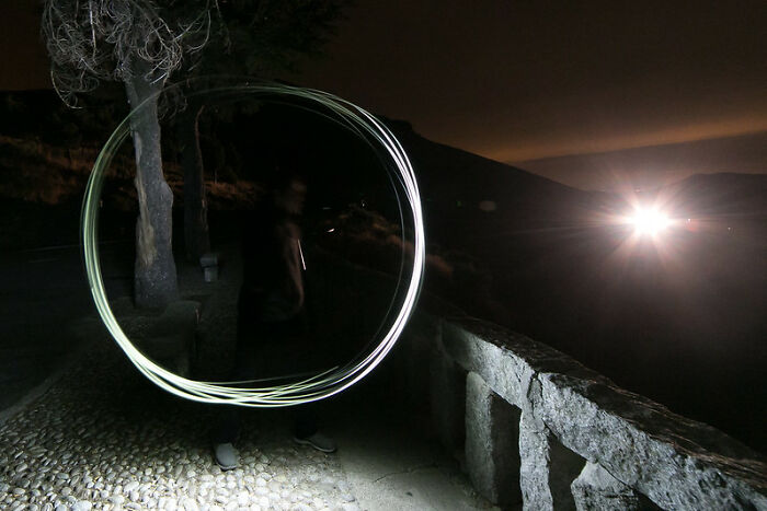Person creating light circle with motion at night outdoors, illustrating things guys should never say to partners theme.