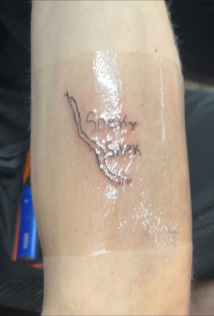 Close-up of a poorly done tattoo labeled "Sneaky Snex" on an arm, showcasing a regrettable tattoo design.