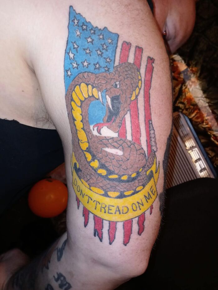 Tattoo of a snake on an American flag background with the phrase "Don't Tread on Me," criticized in a Facebook group.