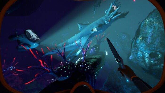Underwater scene from an indie game showing a diver holding a knife near a large sea creature with glowing coral nearby.