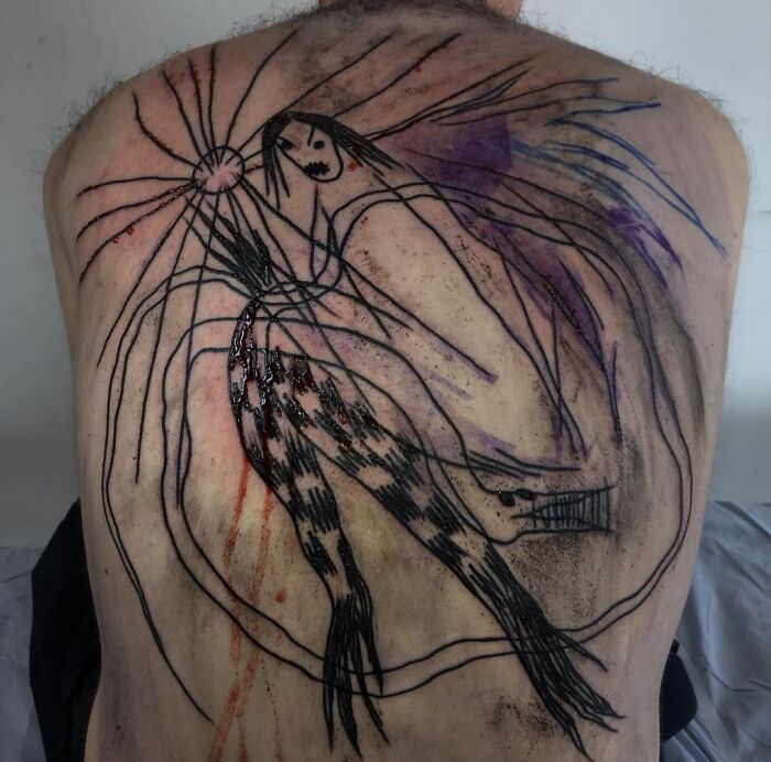 Tattoo design on person's back with abstract lines and shapes, possibly representing hair and a face, shared in an online group.