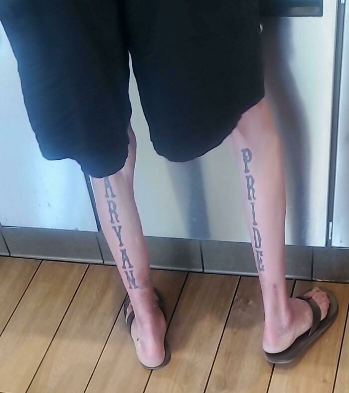 Person with controversial tattoo text on calves standing in flip-flops. Worst tattoos example.