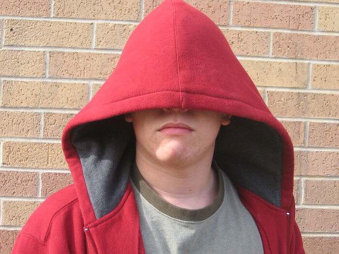 Young man in a red hoodie with hood over face symbolizing things guys should never say to their partners in relationships.