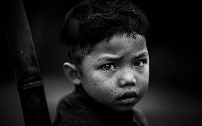 Portrait of a young boy with an intense expression, captured in a powerful black and white photograph by a photographer.