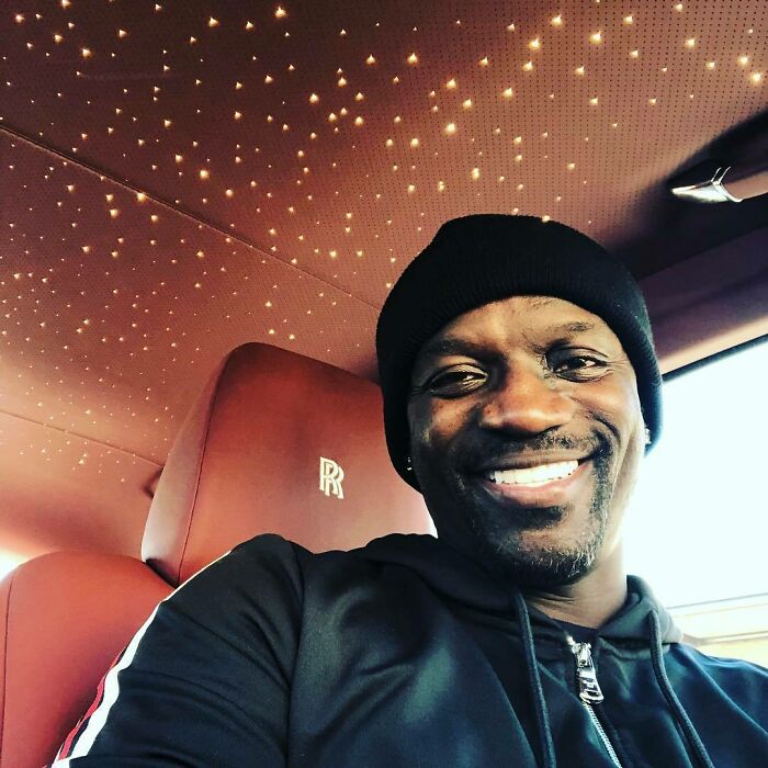 Smiling man inside luxurious car with star-lit ceiling, symbolizing celebrity wealth.