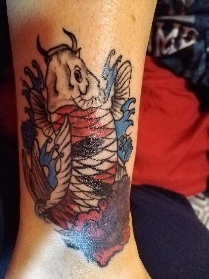 Colorful koi fish tattoo with red and blue ink on leg.
