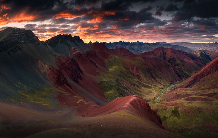Colorful Peruvian Andes mountains at sunset with dramatic clouds and vibrant red and green landscape view.