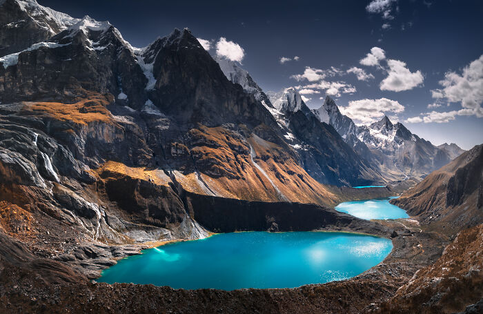 Turquoise lakes nestled among rugged peaks in the scenic Peruvian Andes under a bright blue sky.
