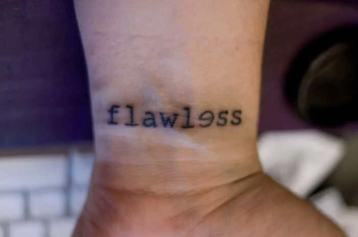 Wrist tattoo of the word 'flawless' with a backward '3' as 'E', considered by some as a red flag.