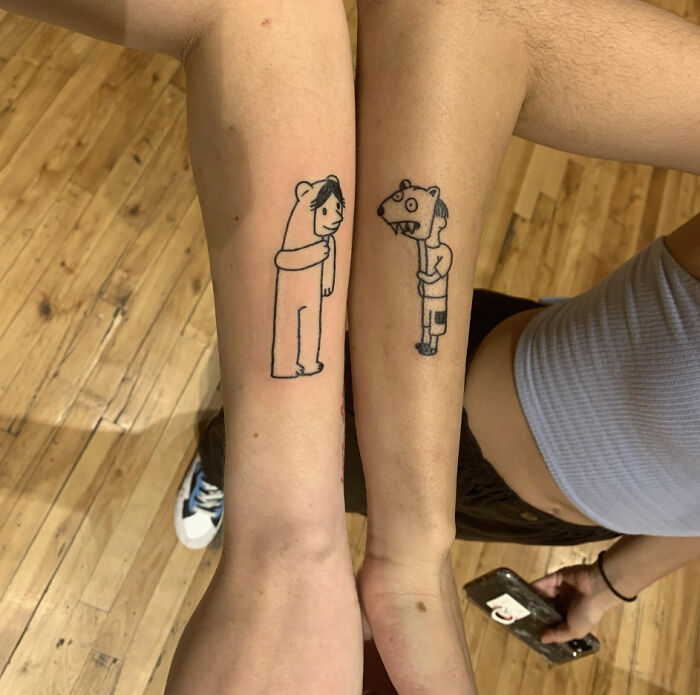 Two arms with simple line tattoos of cartoon figures, possibly signaling major red flags.