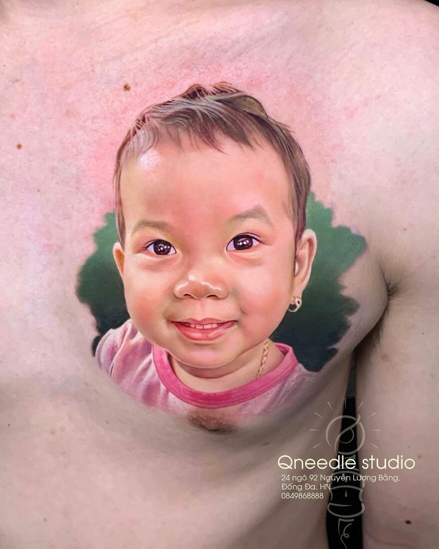 Hyper-realistic tattoo of a smiling child's face on a person's chest.