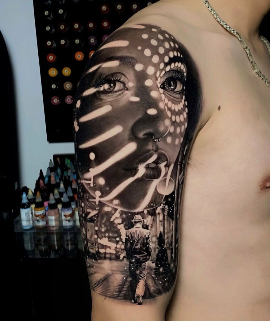 Hyper-realistic tattoo of a woman's face with lighting patterns and a man walking in a cityscape on a person's arm.