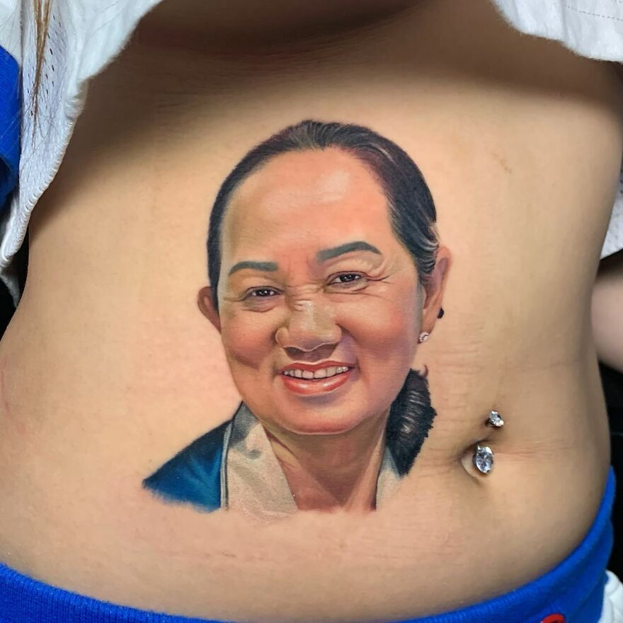 Hyper-realistic tattoo of a smiling woman on abdominal skin, showcasing detailed facial features and jewelry.