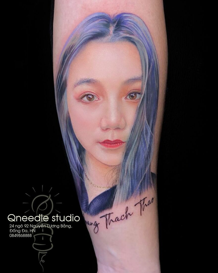 Hyper-realistic tattoo of a woman's face with blue hair and red lips on an arm.