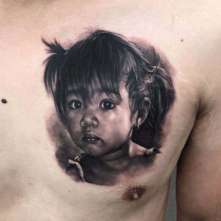 Hyper-realistic tattoo of a child's portrait on skin, showcasing intricate detail and lifelike quality.