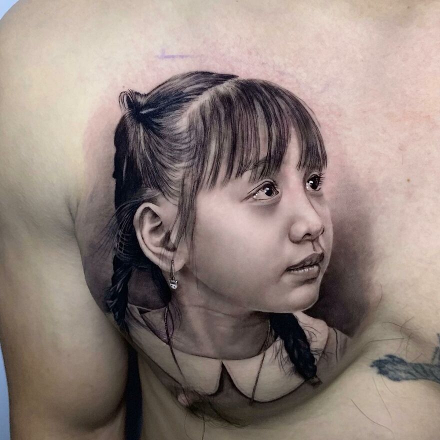 Hyper-realistic tattoo of a young girl with braided hair, capturing intricate facial details on the skin.