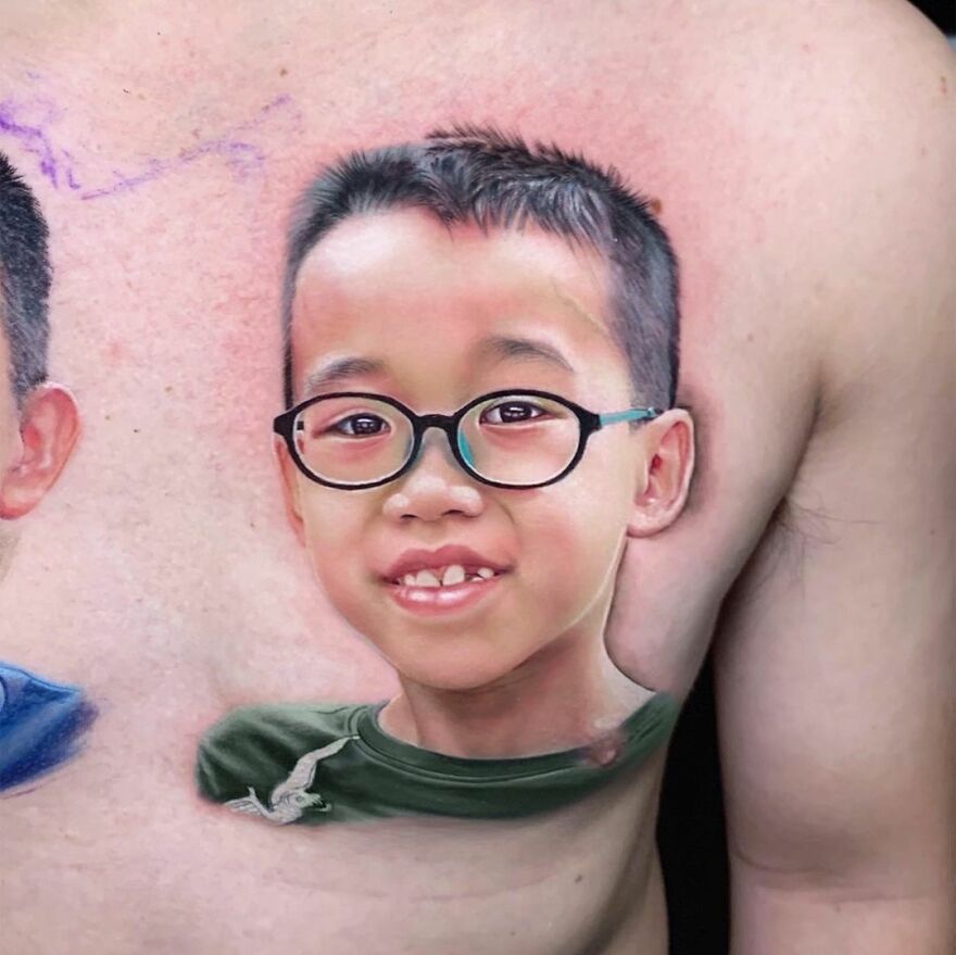 A hyper-realistic tattoo of a young boy with glasses, detailed and lifelike, on someone's chest.