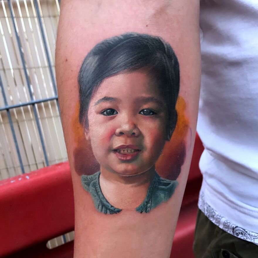 Hyper-realistic tattoo of a child's face on an arm, showcasing lifelike detail and vibrant colors.