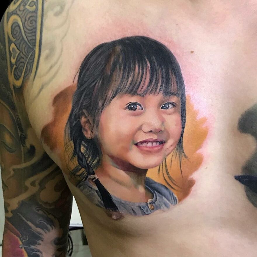 Hyper-realistic tattoo of a smiling child on a person's chest, showcasing intricate detail and lifelike color.