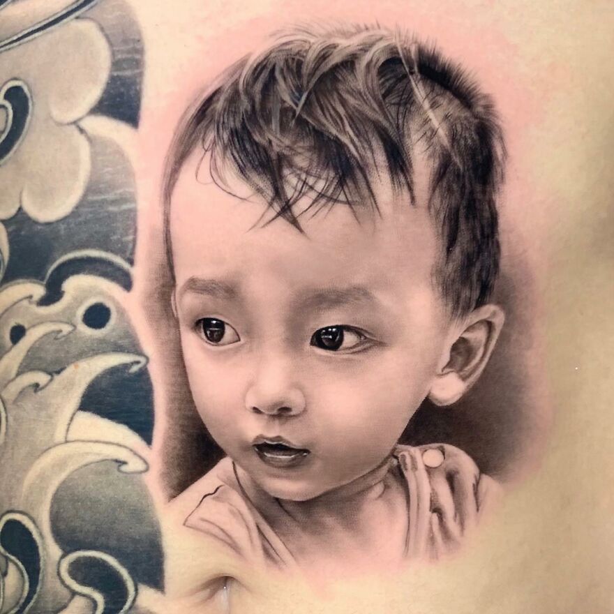 Hyper-realistic tattoo of a child's face on skin with detailed shading and realistic texture.