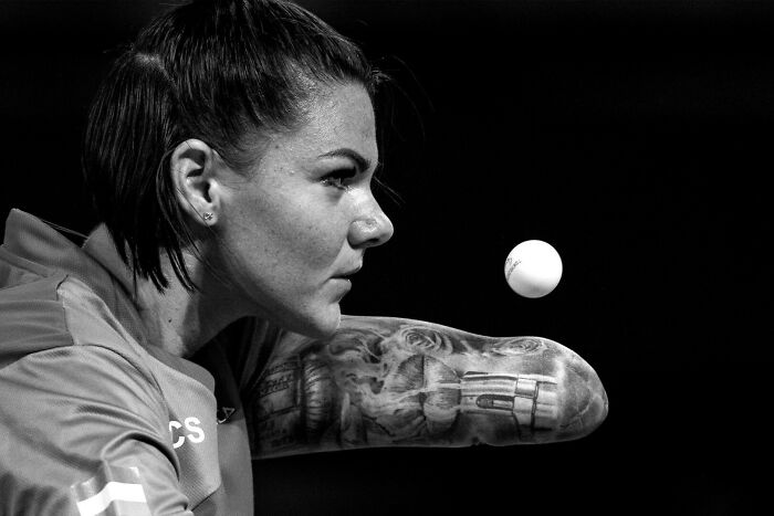 Female table tennis player focusing intensely on the ball during one of the best moments in sports photography.