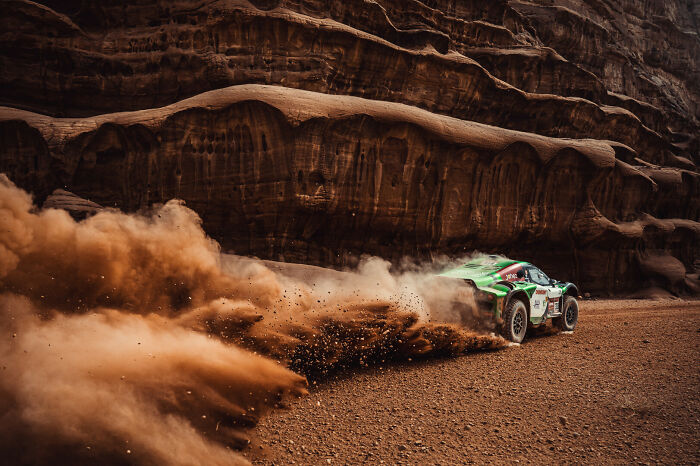 Rally car kicking up dust racing through rocky terrain, capturing one of the best moments in sports photography 2022.