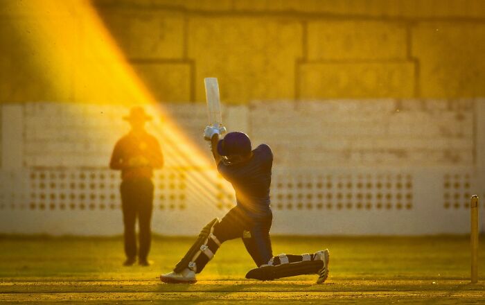 Cricket player hitting a shot during golden hour, capturing one of the best moments in sports photography 2022.