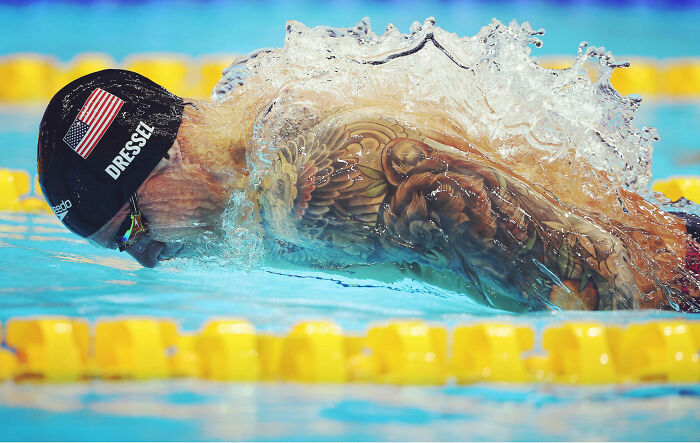Swimmer with tattoos competing in a pool, captured in action as one of the best moments in sports photography 2022.