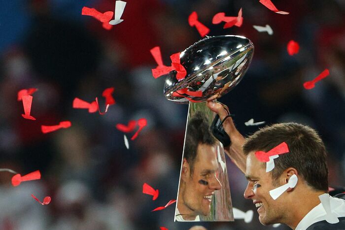 Champion holding a trophy amid red and white confetti celebrating one of the best moments in sports in 2022.