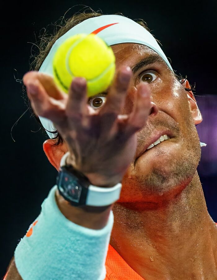 Tennis player intensely focused on serving the ball, captured as one of the best moments in sports photography.