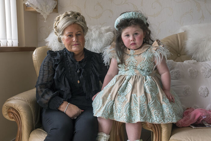 Portrait of woman and young girl in elegant vintage clothing seated on a sofa, capturing powerful portrait photography.