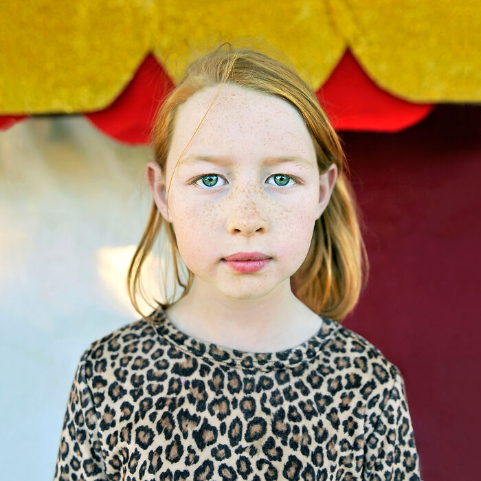 Close-up portrait of a young girl with freckles and green eyes, showcasing powerful portraits by photographers worldwide.