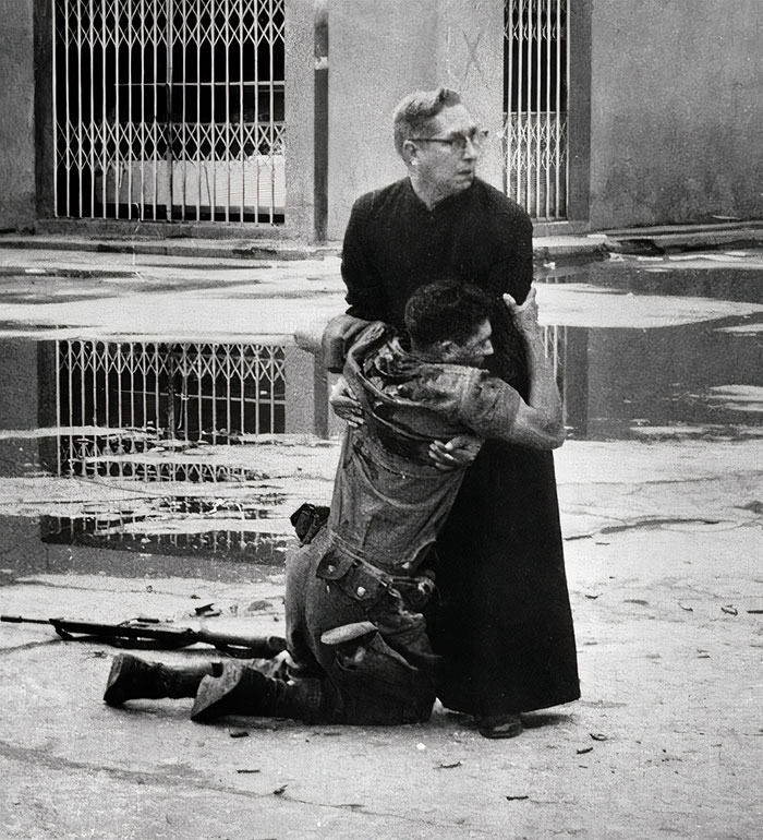 Father Luis Manuel Padilla Holds A Wounded Government Rifleman Shot Down In The Streets Of Puerto Cabello, Venezuela
