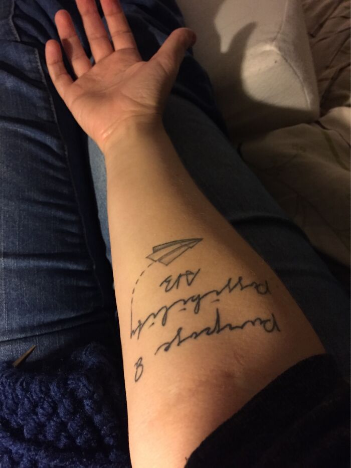 Tattoo on forearm featuring a paper airplane and cursive text with the keywords "last tattoo."