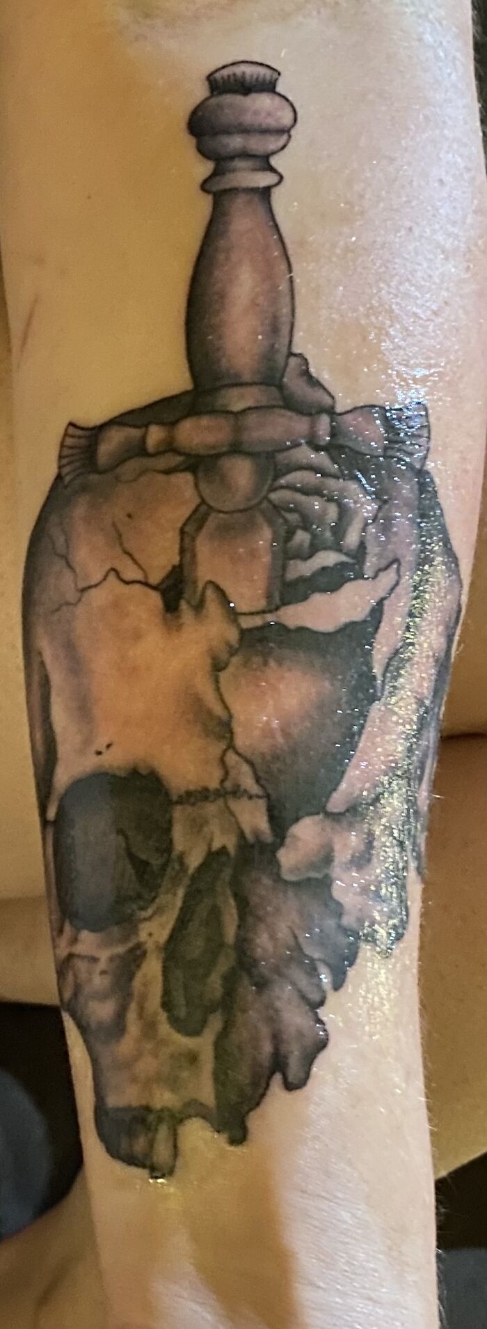 Tattoo of a c*****d skull with a chess piece on top, showcasing unique art and design.